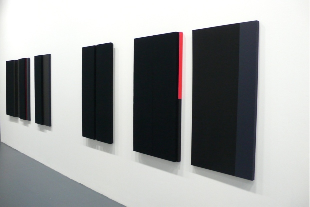 A series of painting of either plain black canvas or black and another color