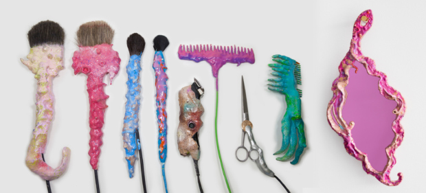 Make up brushes, comb, scissors, and a mirror that looks like sea shells (cropped)